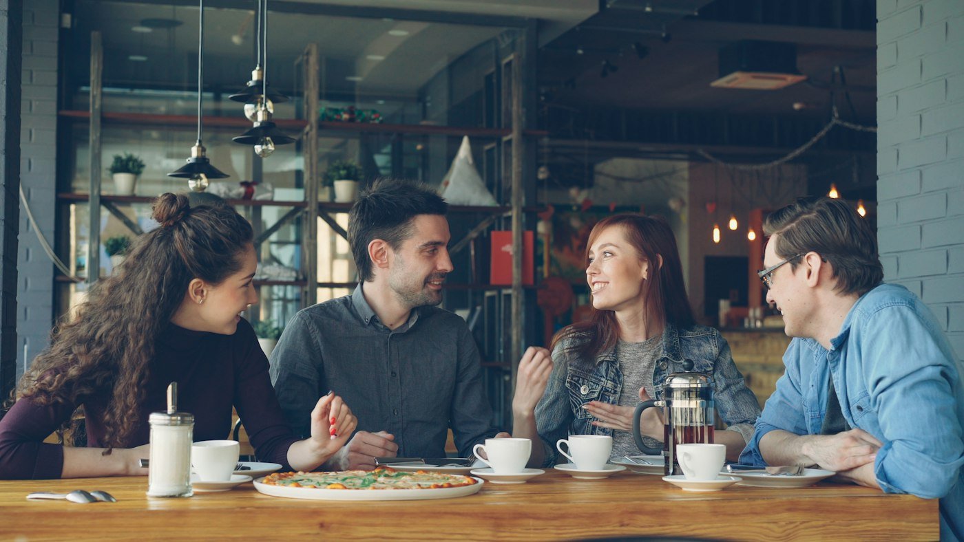 Cuatro personas conversan en una cafetería.